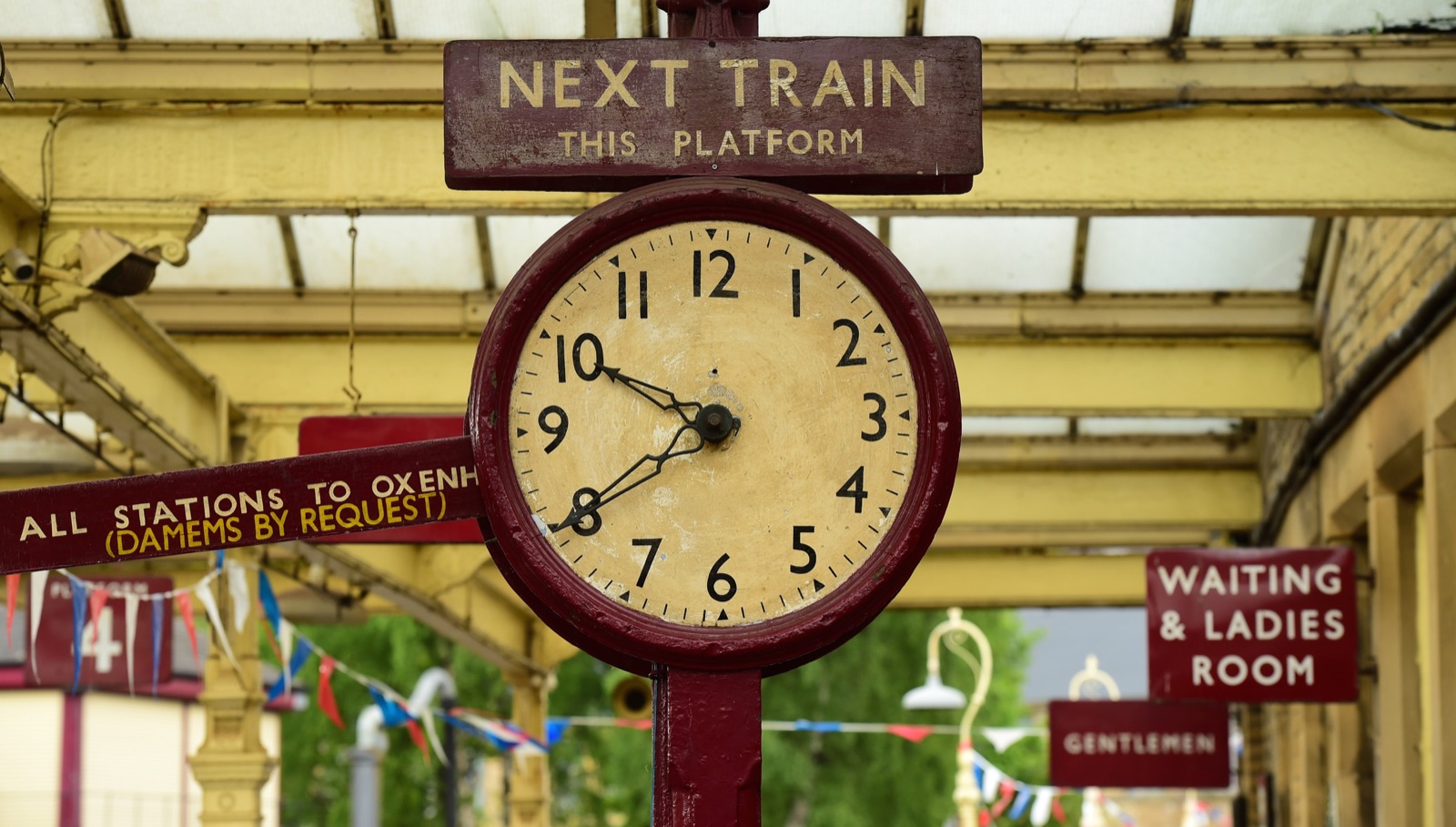 Horloge de quai de gare sous un panneau « Next train »
